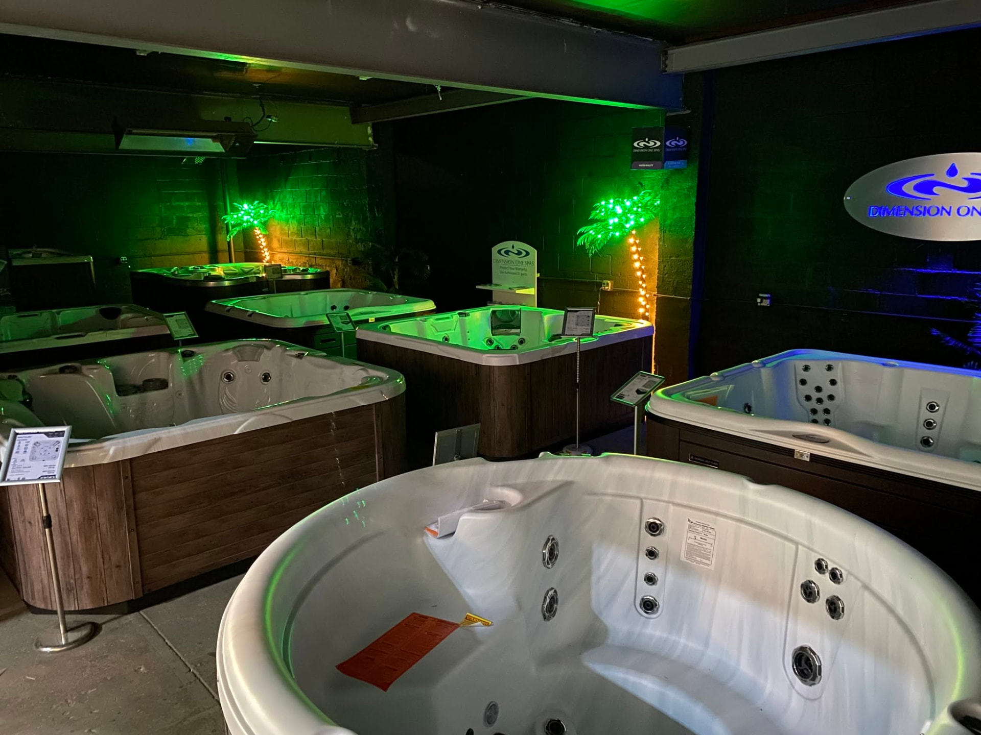 Dimension One hot tubs on display under green lighting in the Island Pools Englewood showroom